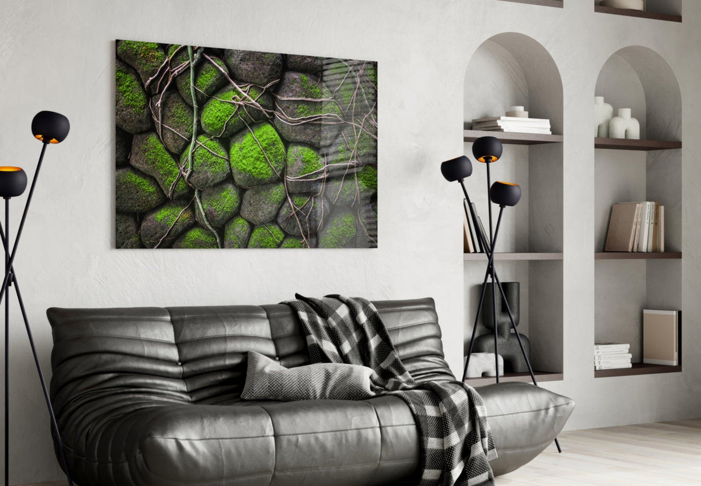 Mossy Stones Glass Wall Art displayed above a black leather sofa in a modern living room with white built-in shelving.