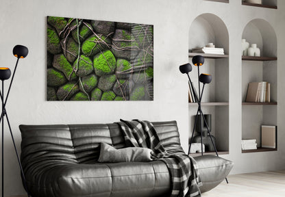 Mossy Stones Glass Wall Art displayed above a black leather sofa in a modern living room with white built-in shelving.