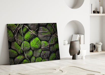 Mossy Stones glass wall art leaning against white wall in minimalist interior with decorative objects and shelving.