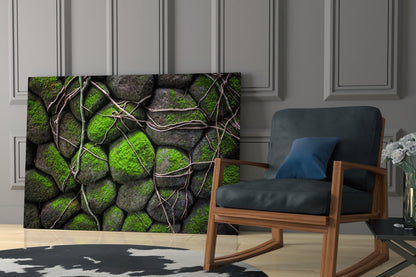 Mossy Stones Glass Wall Art displayed in a modern living room beside a wooden-framed chair, showing bright green moss on gray rocks with brown vine details.