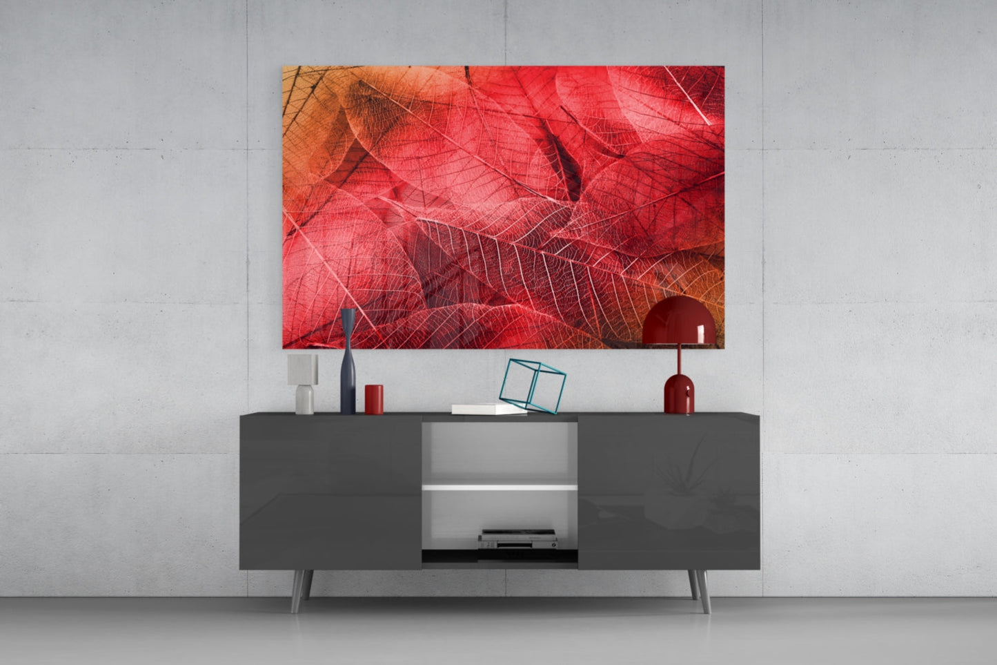 Red and orange leaf-veined glass artwork displayed above a dark gray media console in a minimalist living room setting.