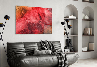 Red and orange leaf-textured glass art displayed above black leather sofa in modern living room interior.