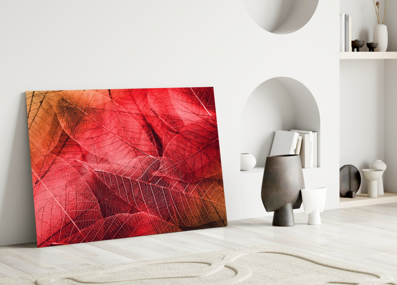 Red and orange macro leaf glass artwork leaning against white wall in minimalist interior setting.