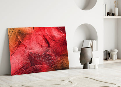 Red and orange macro leaf glass artwork leaning against white wall in minimalist interior setting.