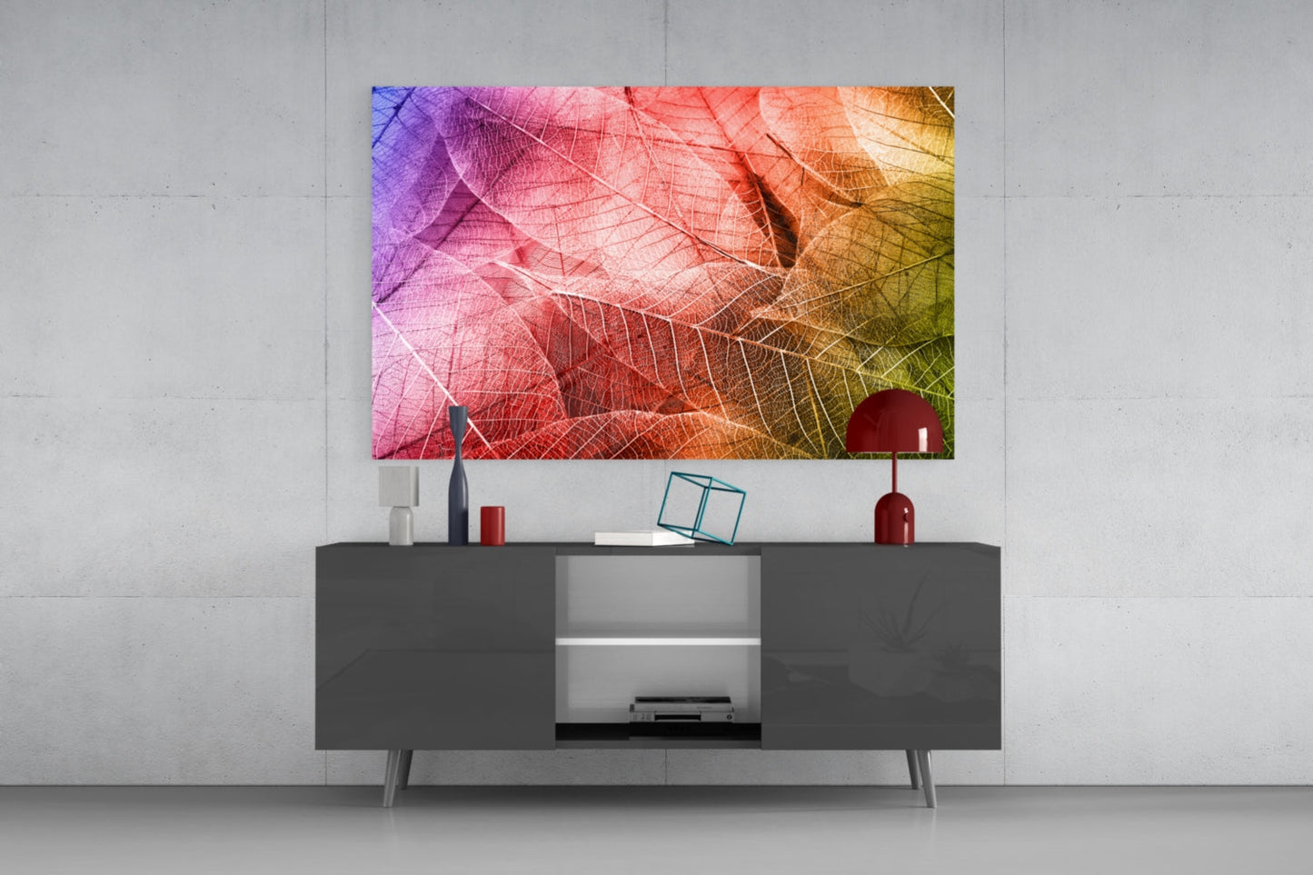 Colorful macro leaf glass art with purple, pink, orange and yellow tones displayed above dark grey media console in modern living room setting.