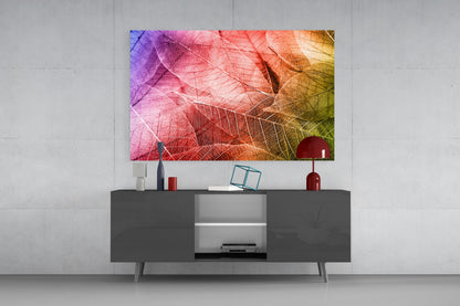 Colorful macro leaf glass art with purple, pink, orange and yellow tones displayed above dark grey media console in modern living room setting.