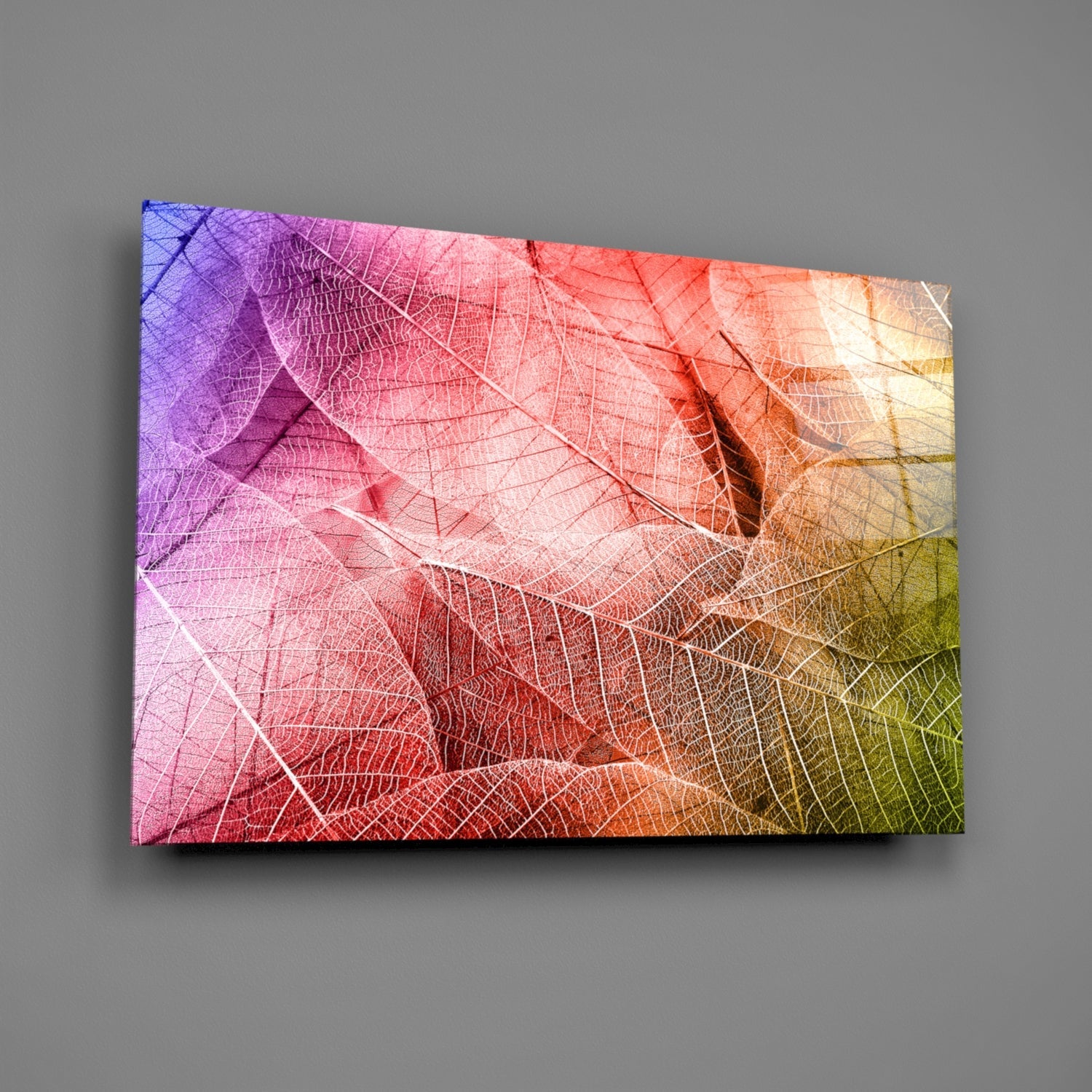 Glass wall art displaying translucent overlapping leaves in a gradient from purple and pink to orange and yellow-green.