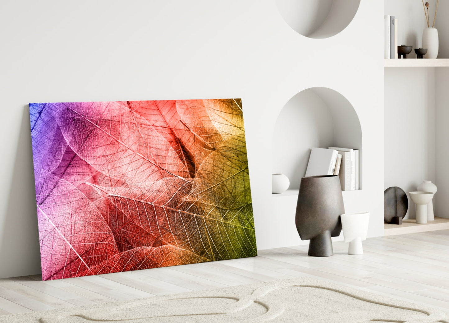 Colorful macro leaf glass art leaning against white wall in minimalist room with decorative objects.