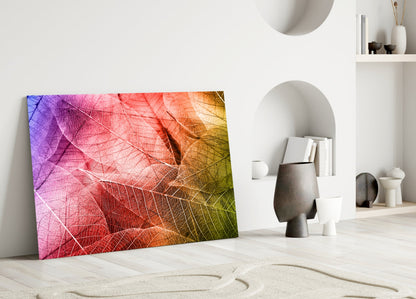 Colorful macro leaf glass art leaning against white wall in minimalist room with decorative objects.
