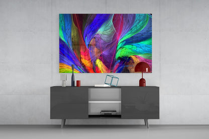 Colorful abstract glass wall art with swirling blue, purple, green, and red patterns displayed above a dark gray media console in a modern living room setting.