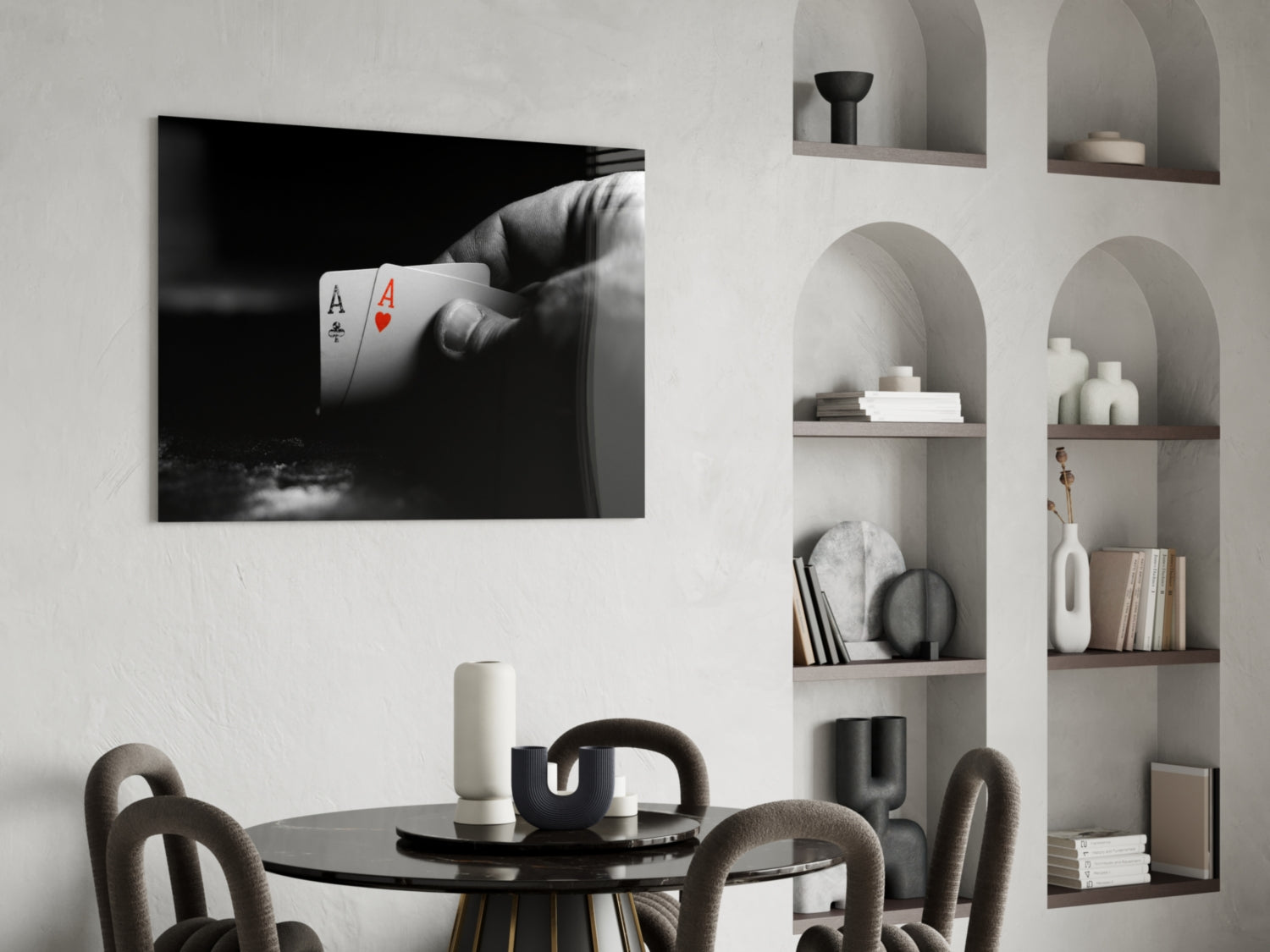 Black and white glass wall art displaying a hand holding two aces playing cards mounted above a round black dining table.