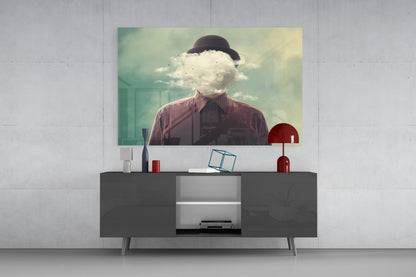 Surreal artwork displayed on dark media console showing man wearing bowler hat with white cloud obscuring his face against green-tinted background.