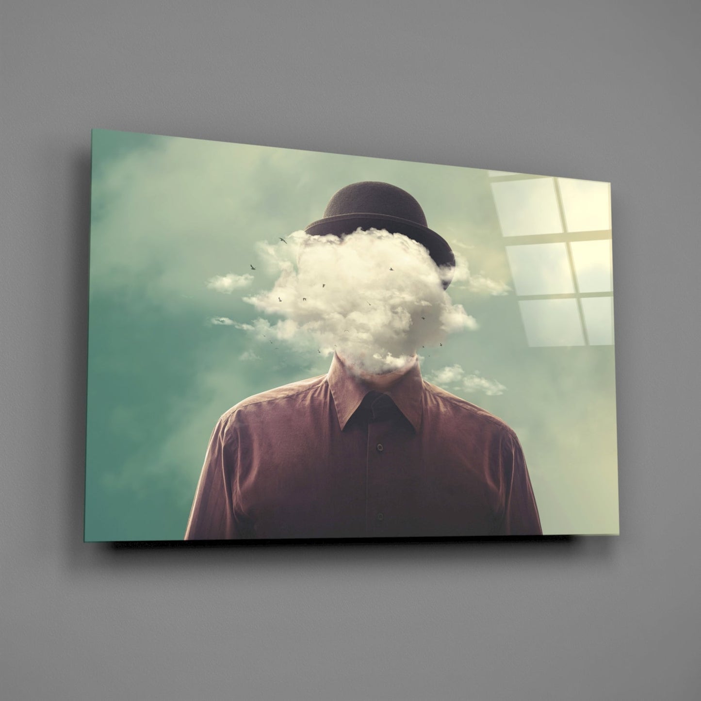 Man wearing maroon shirt and bowler hat with cloud replacing head, mounted on gray wall as glass panel art.