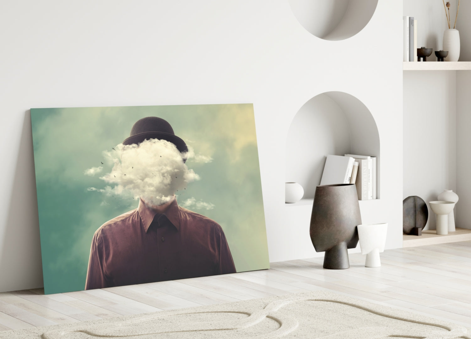 Surreal glass wall art leaning against white wall displays figure with cloud replacing head wearing burgundy shirt against turquoise-yellow gradient background.