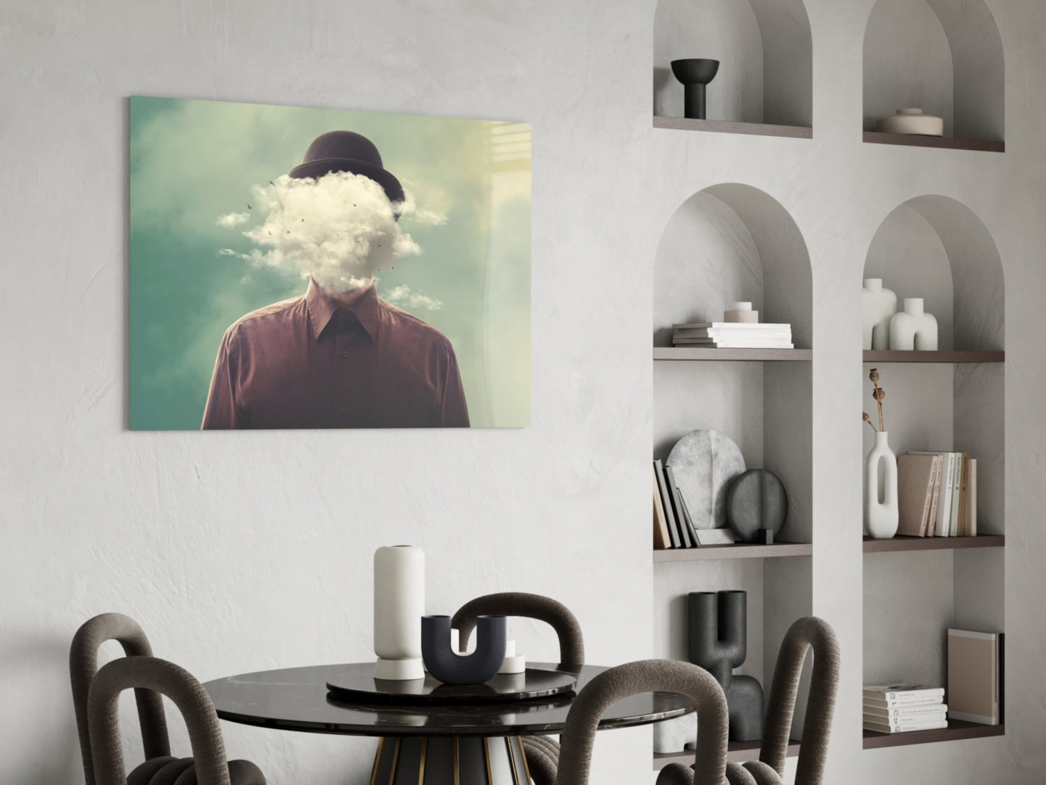 Surreal glass wall art depicting a person with a cloud replacing their head, wearing burgundy shirt against turquoise sky, displayed above dining table.