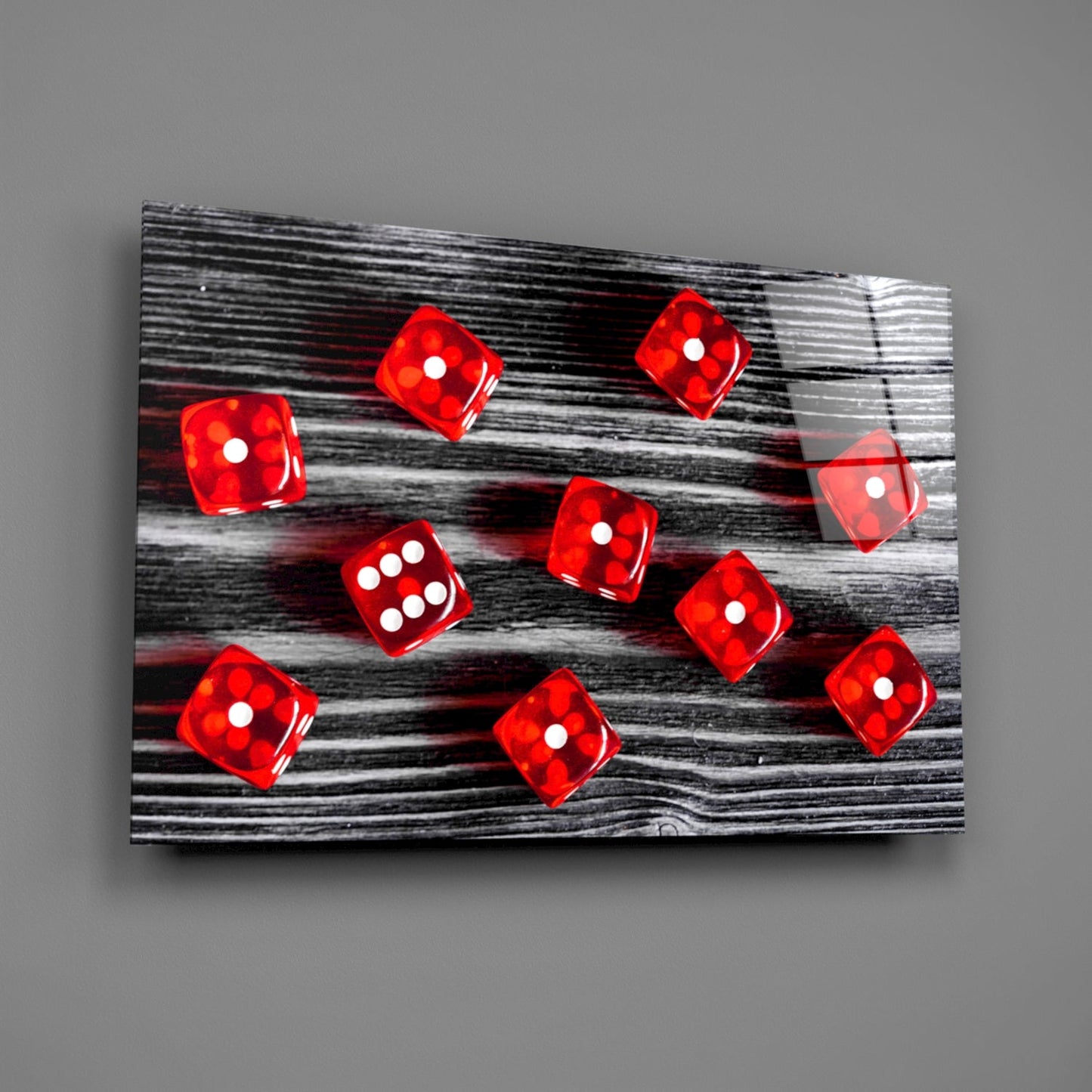 Red translucent dice with white dots scattered on black and white wood grain glass panel, angled perspective view.