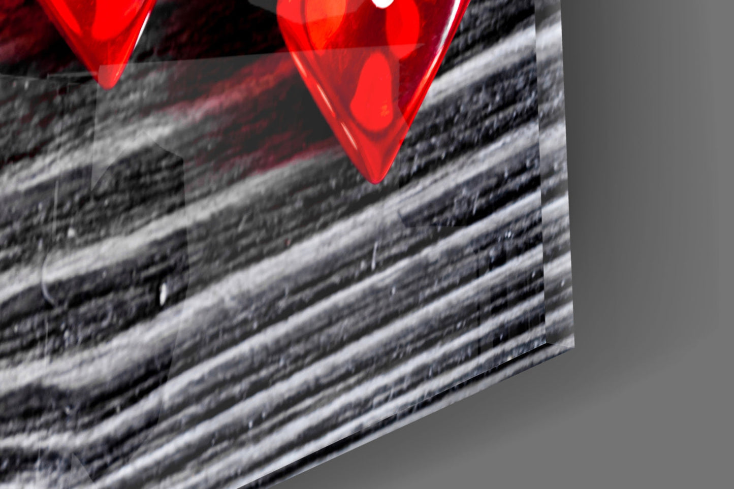 Close-up detail of red glass dice against textured gray and white striped surface, angled perspective.