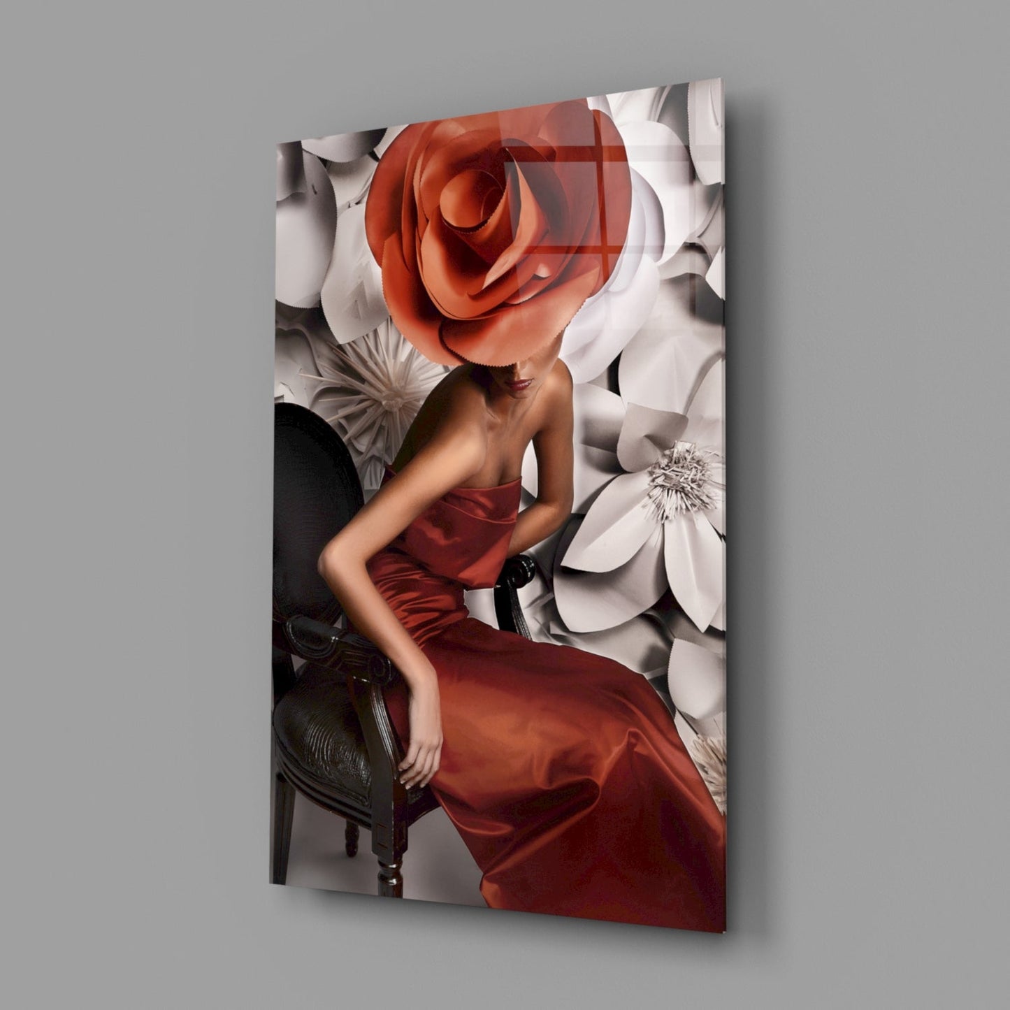 Glass wall art displaying a woman in red dress with oversized red and white flower head, mounted on gray wall.