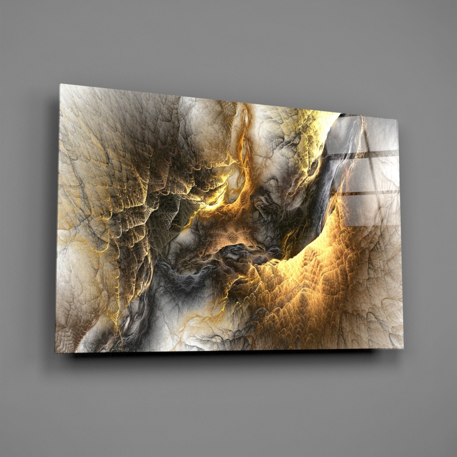 Golden Chaos Glass Wall Art displayed at an angle against a gray wall, showing textured golden and gray abstract patterns with metallic accents.