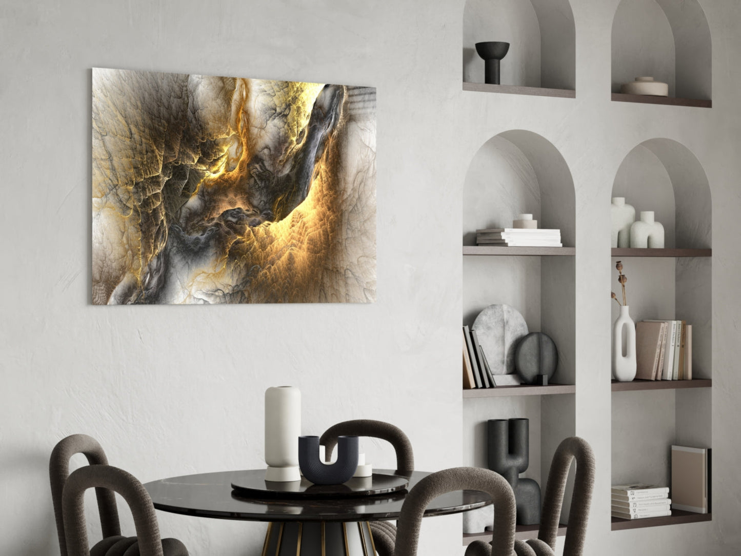 Golden Chaos glass wall art hanging above a black round dining table with grey upholstered chairs in a modern interior with white built-in shelving.