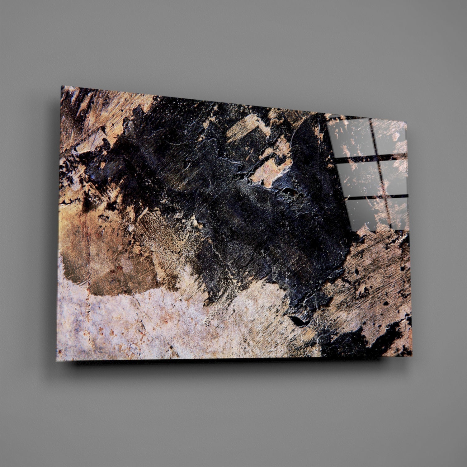 Angled view of glass wall art displaying weathered black, tan, and white paint textures with metal frame details on right edge against gray background.