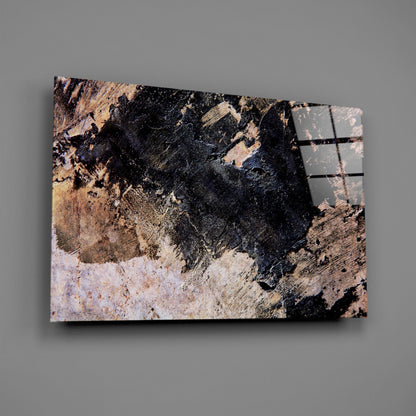 Angled view of glass wall art displaying weathered black, tan, and white paint textures with metal frame details on right edge against gray background.