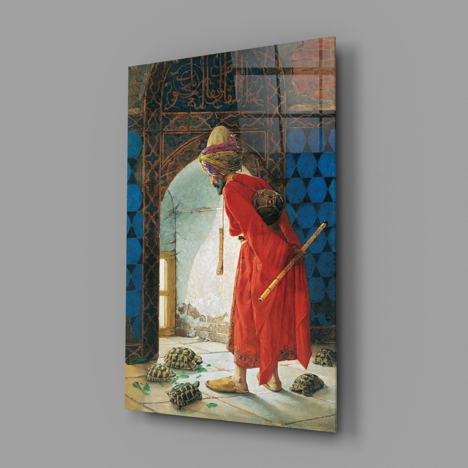 A framed glass wall art print displaying an orientalist painting of a figure in red robes and yellow turban observing tortoises in a blue-tiled courtyard.