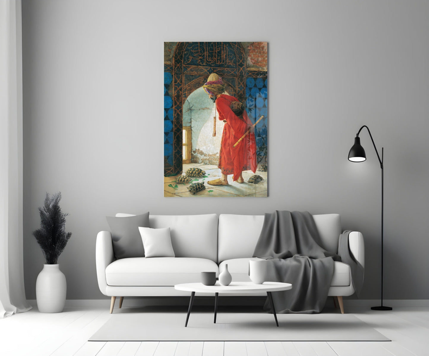 Turtle Trainer glass wall art displayed above a white sofa in a minimalist living room setting, showing two robed figures with decorative blue and ornate backgrounds.
