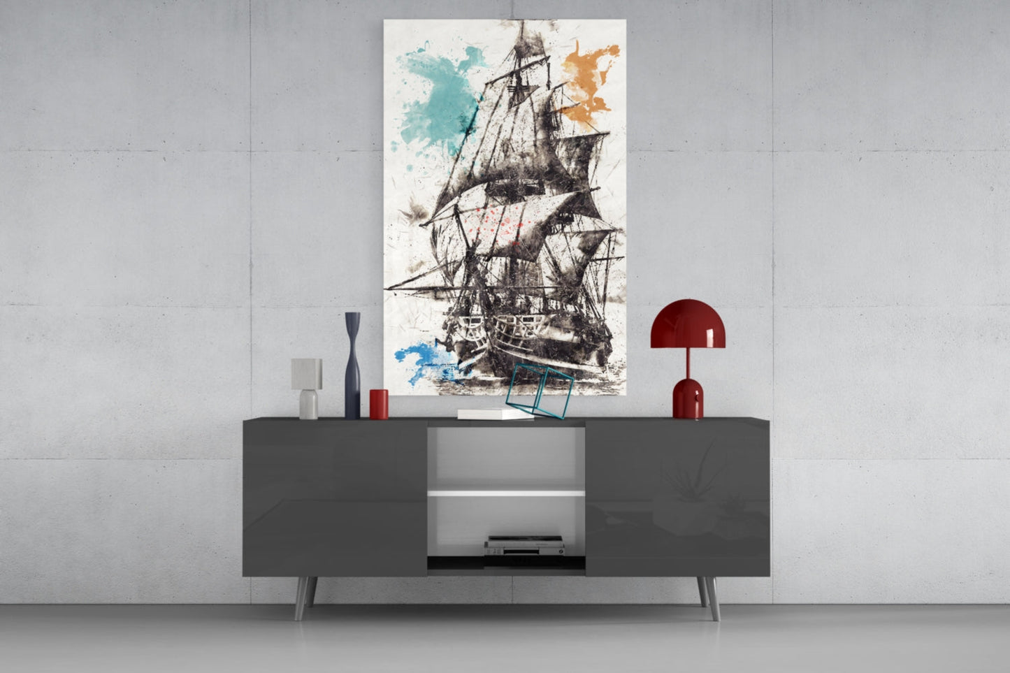 Glass wall art depicting a detailed sailing ship with watercolor splashes in turquoise and gold displayed above a dark console table.
