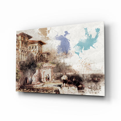 Angled view of glass wall art featuring a watercolor-style historical European courtyard scene with architectural buildings, figures, and blue-teal map overlay.