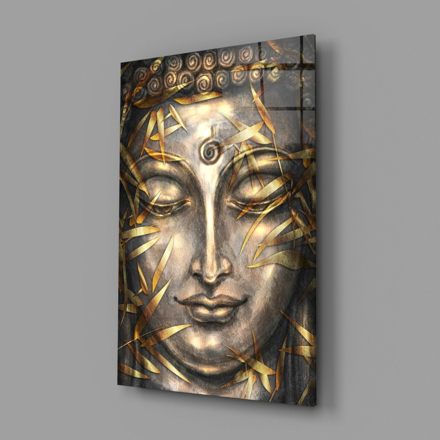 Glass wall art featuring a serene Buddha face with closed eyes, gold leaf accents, and ornamental spiral details, displayed at an angle against gray background.