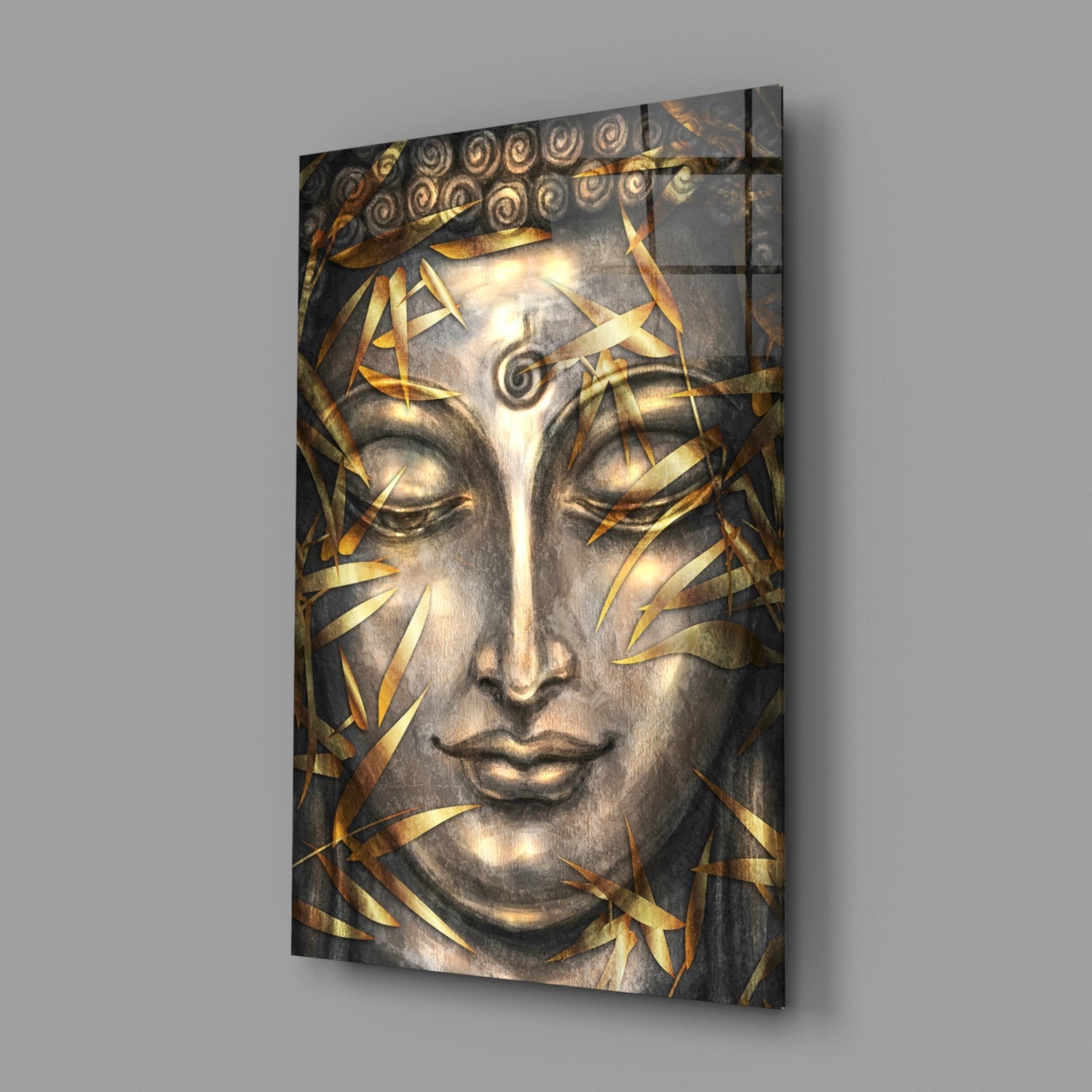Glass wall art featuring a serene Buddha face with closed eyes, gold leaf accents, and ornamental spiral details, displayed at an angle against gray background.