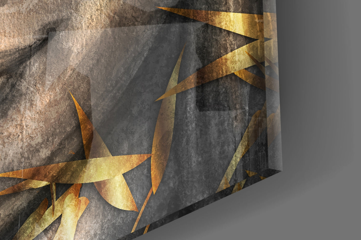 Close-up angled view of textured glass wall art with gold leaf accents overlaying gray stone surface.