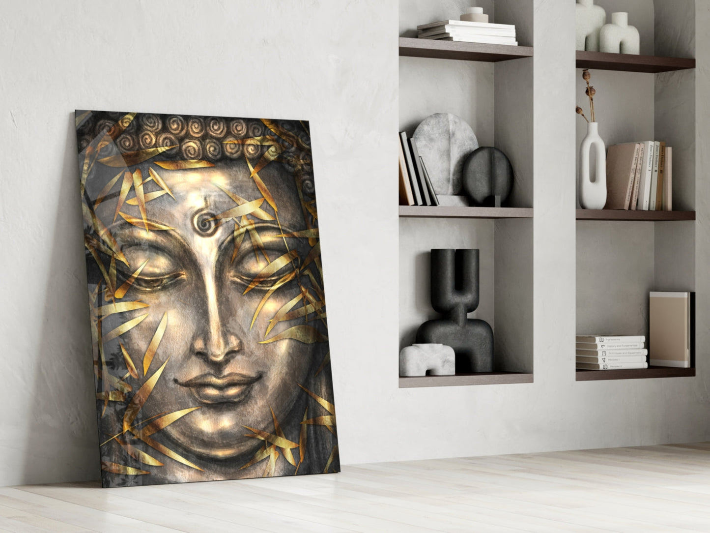 Golden and grey Buddha head canvas art leaning against white wall beside shelving unit with decorative objects and books.