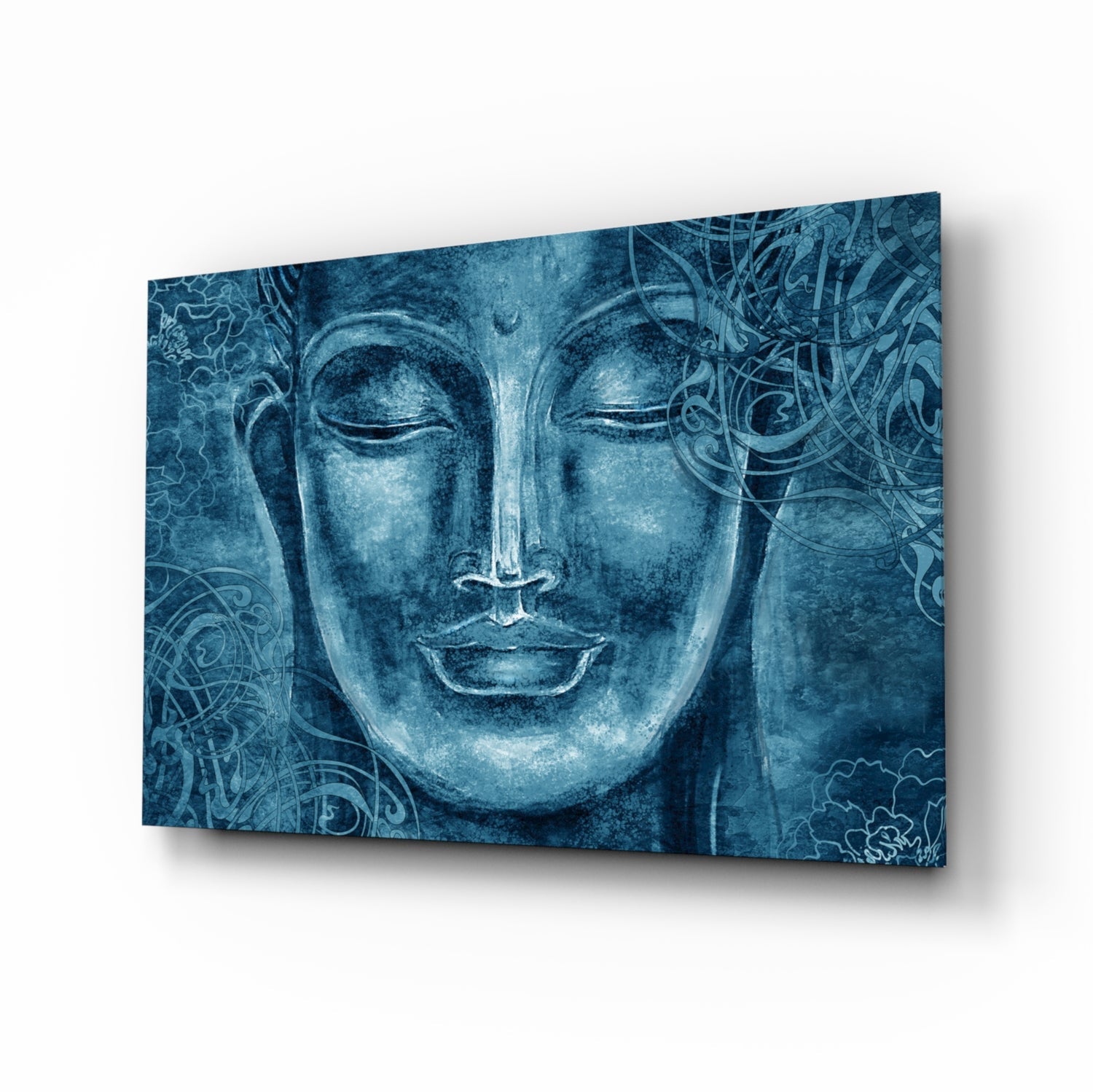 Blue tinted glass wall art panel displaying a serene Buddha face with ornamental patterns, photographed at an angle against white background.
