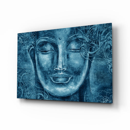 Blue tinted glass wall art panel displaying a serene Buddha face with ornamental patterns, photographed at an angle against white background.