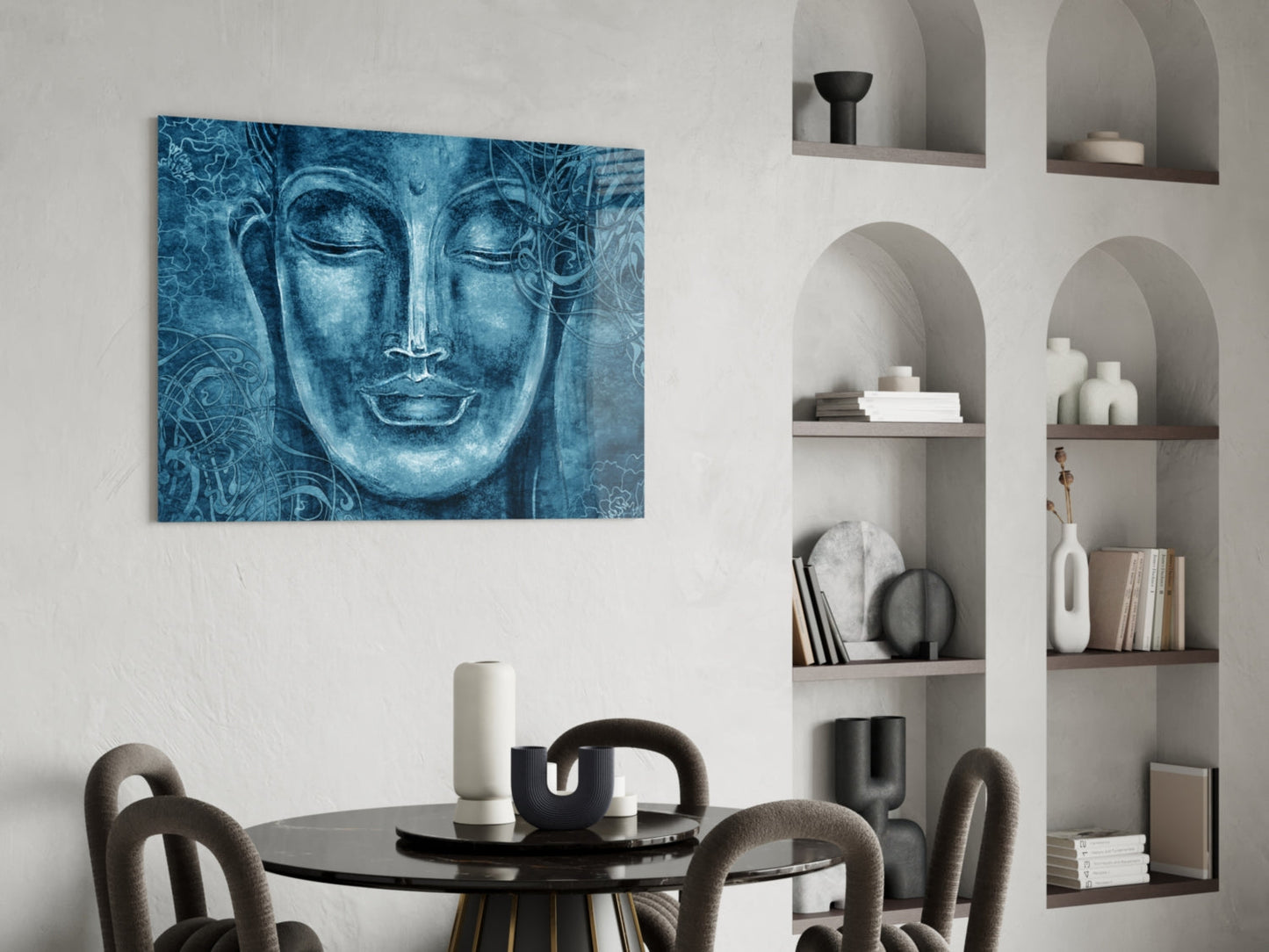 Blue glass wall art depicting a serene Buddha face with ornamental patterns, displayed above a black dining table in a minimalist interior.