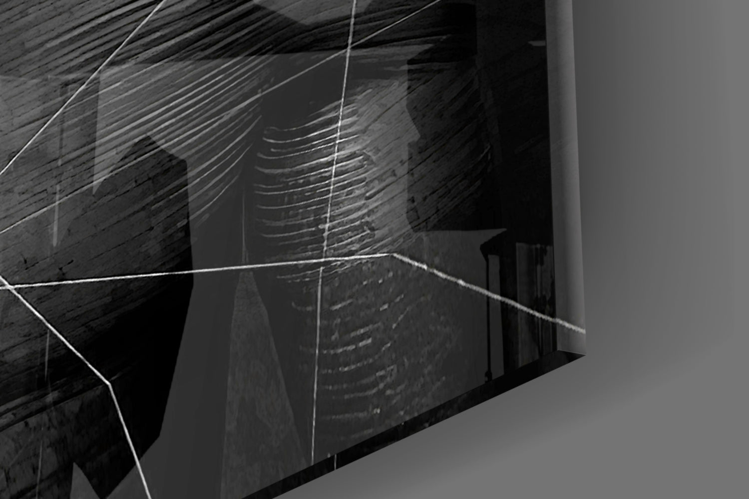 Angled close-up view of gray glass wall art with etched linear patterns and geometric shapes casting shadows.