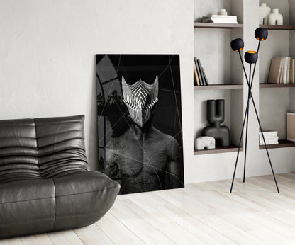 Black and white glass wall art depicting an abstract figure with geometric patterns displayed in a modern living room with gray leather furniture and shelving.