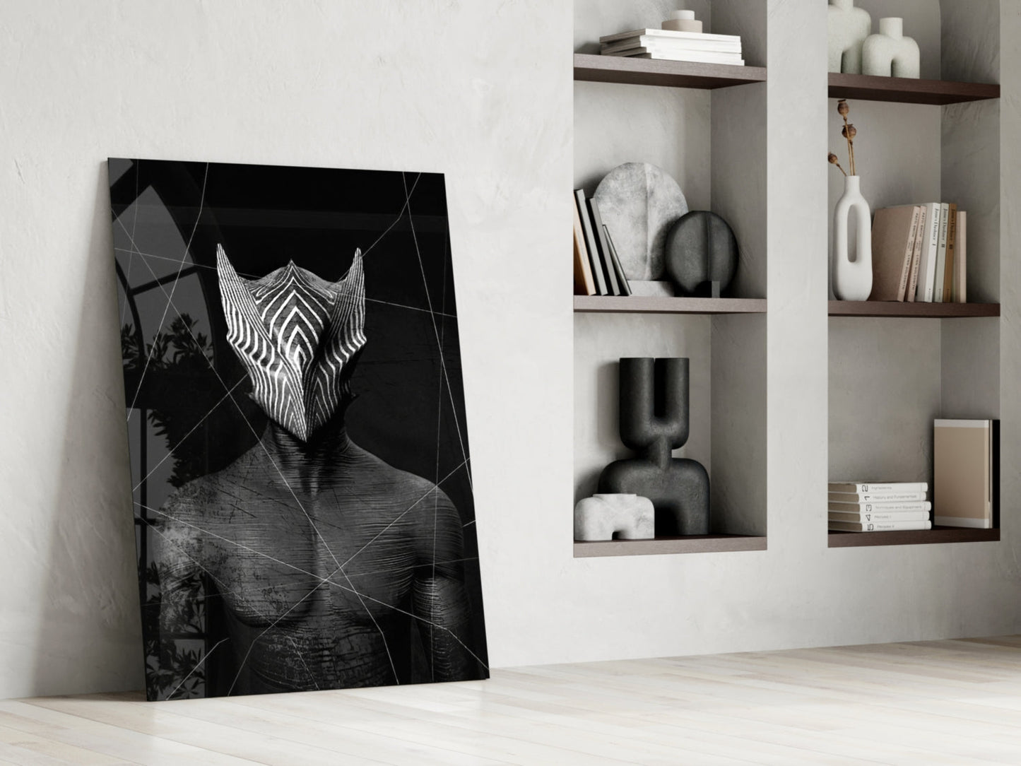 Black glass wall art leaning against white wall displays geometric patterned face mask with white striped design alongside styled shelving.