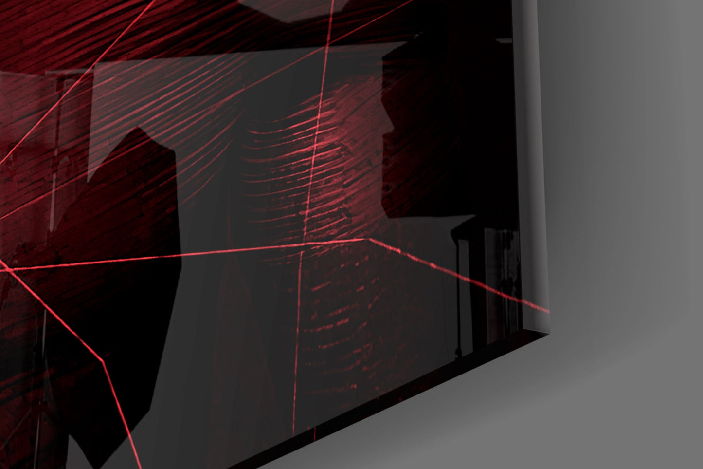 Red laser light projecting geometric patterns on dark glass panels mounted on an interior wall corner.