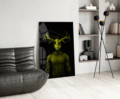 Yellow and black glass wall art depicting a horned humanoid figure displayed in a modern living room with gray sofa and shelving.