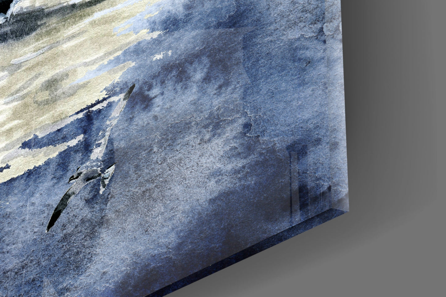 Close-up angled view of glass wall art showing textured blue and white layered surface with dark streaks against gray background.