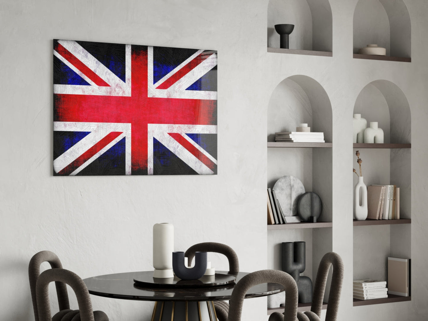 British Union Jack flag glass wall art displayed above a round black dining table with grey chairs in a modern interior with white built-in shelving.