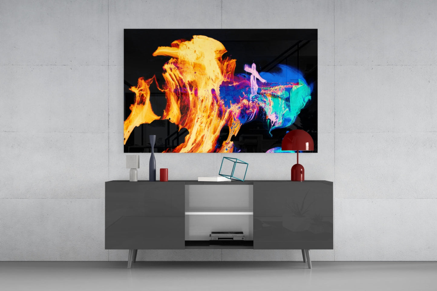 Vibrant glass wall art displaying abstract flames in yellow, orange, and blue mounted above a gray media console in a modern living room setting.