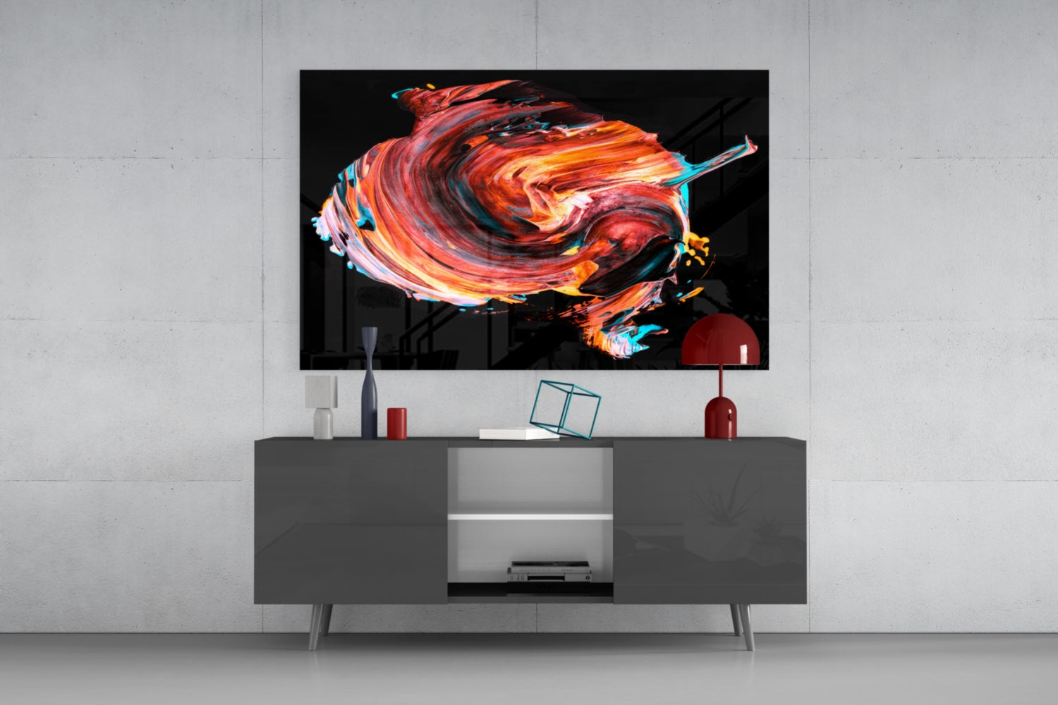 Modern living room display featuring red and orange swirling glass wall art mounted above gray media console with decorative accessories.