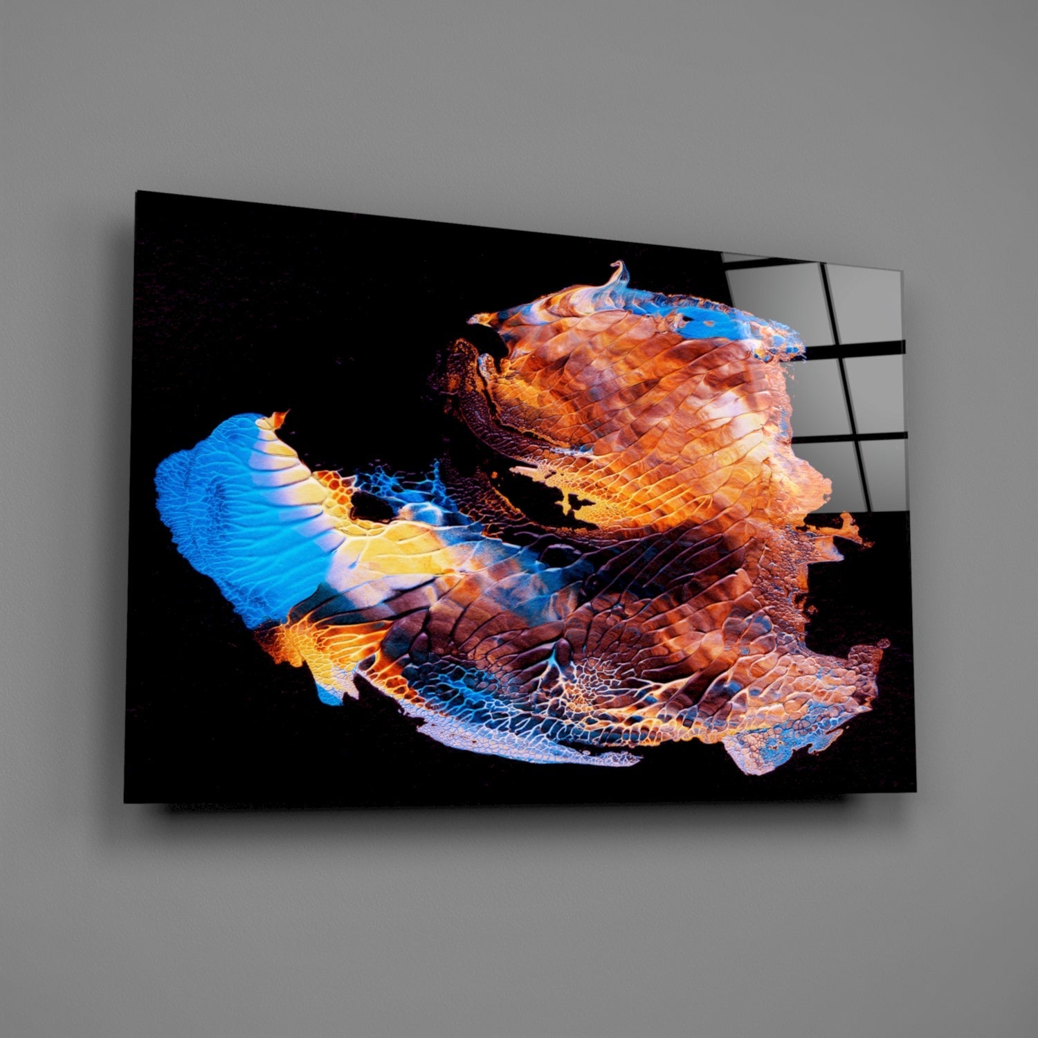 Colorful abstract glass wall art with vibrant blue, orange, and gold layered shapes against black background, displayed at an angle.