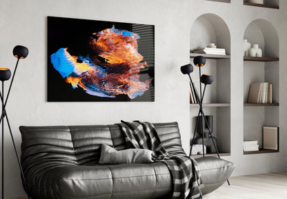 Modern living room with black leather sofa displaying abstract glass wall art featuring blue, orange, and red colorful brushstroke design above it.
