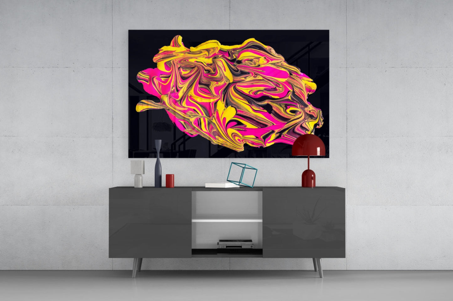Abstract glass wall art with swirling yellow, pink, and gold patterns displayed above a gray media console in a modern living room setting.