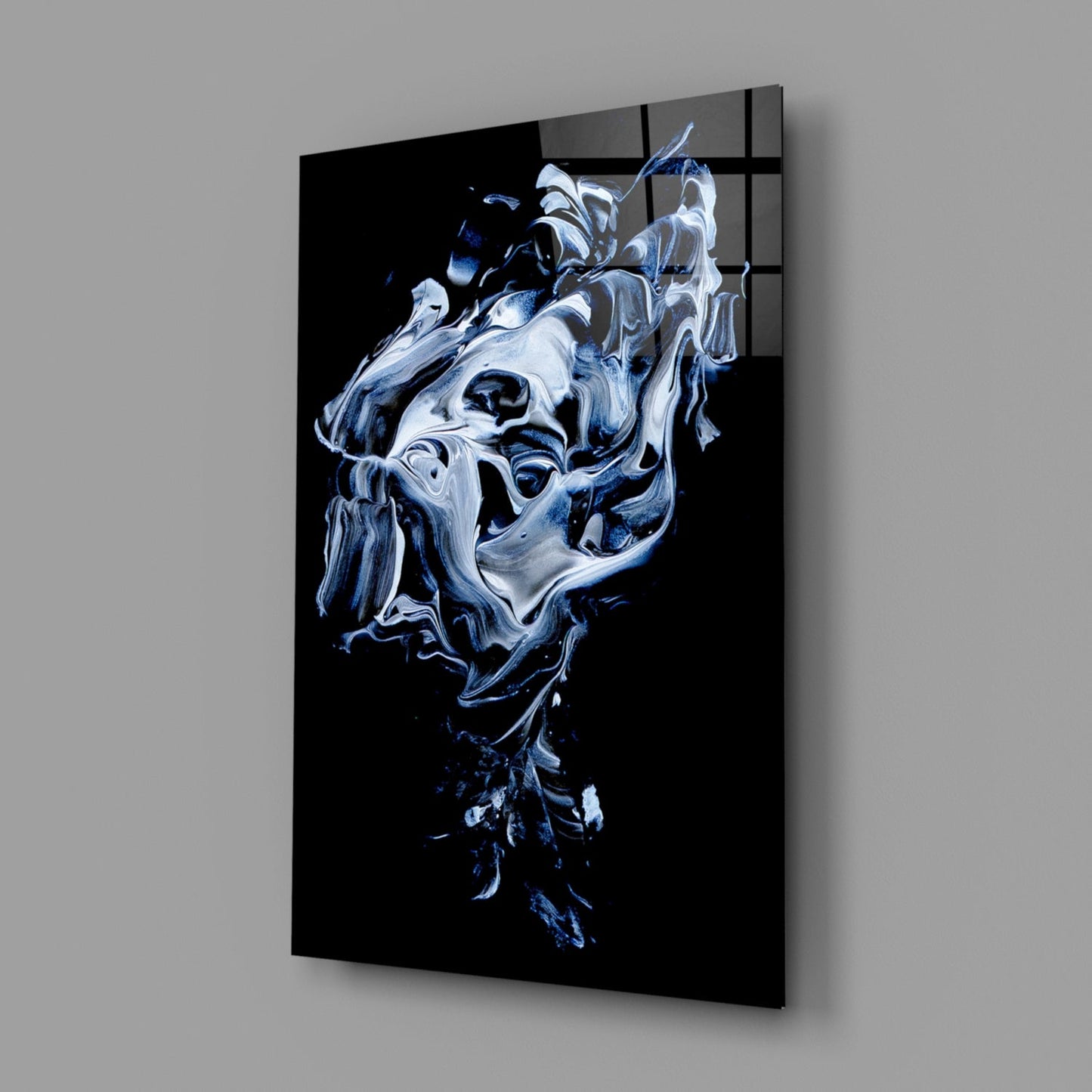 Angled perspective of abstract gray and white glass wall art panel on gray background, showing swirling liquid-like forms with dark accents.